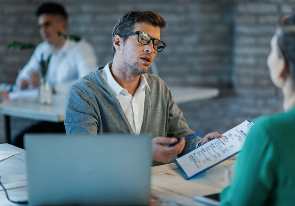 Bank manager discussing with his client about terms of loan agreement during a meeting.