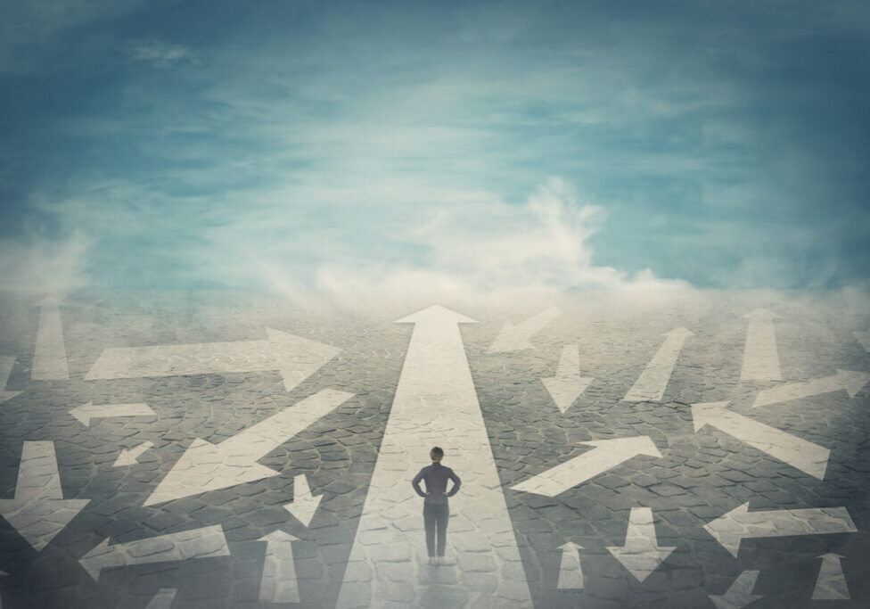 Doubtful person, hands on hips, choosing the way as multiple arrows on the road showing a mess of different directions. Choosing the correct pathway, difficult decision concept, confusion symbol.
