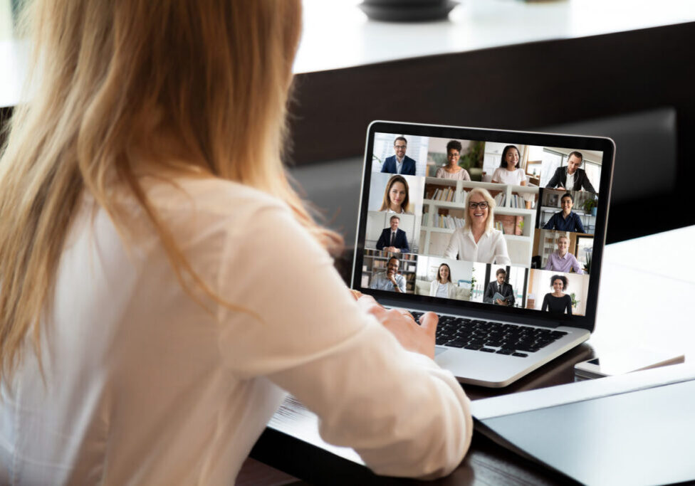 Businesspeople communicating using application webcam laptop view over businesswoman shoulder